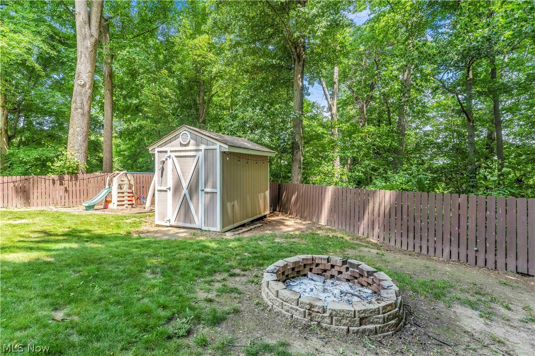 408 River Road Canal Fulton, OH 44614 - Photo 39 of 42 Expansive backyard featuring a privacy fence, wood-sided storage shed, and a stone-built fire pit