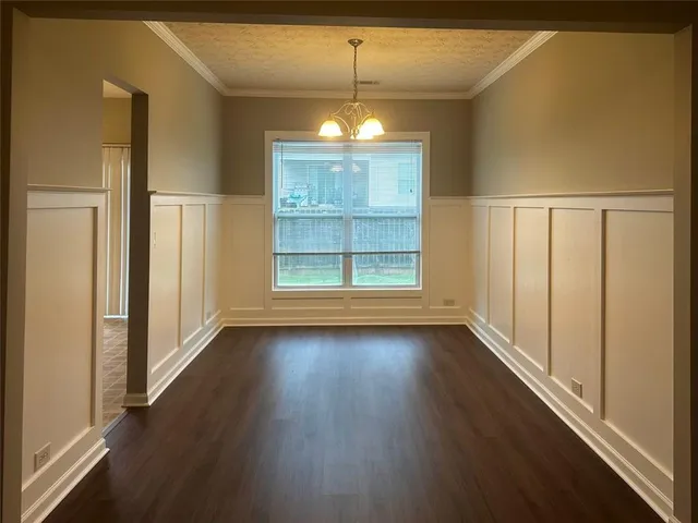 an empty room with wooden floor chandelier and windows