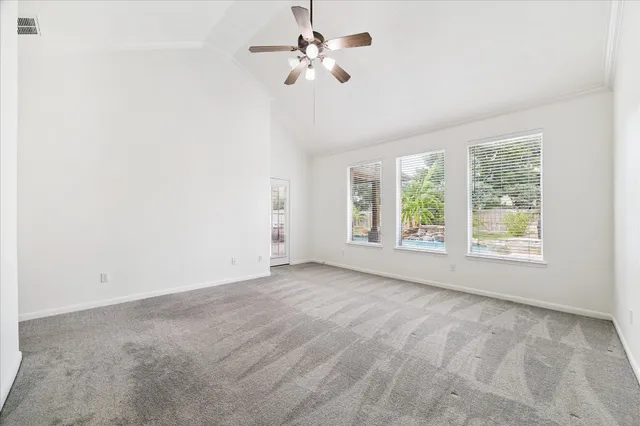 an empty room with a chandelier fan and windows