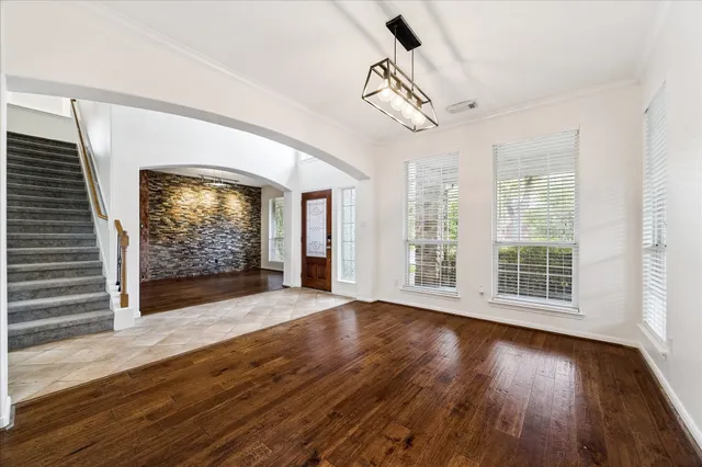a view of empty room with wooden floor and fan