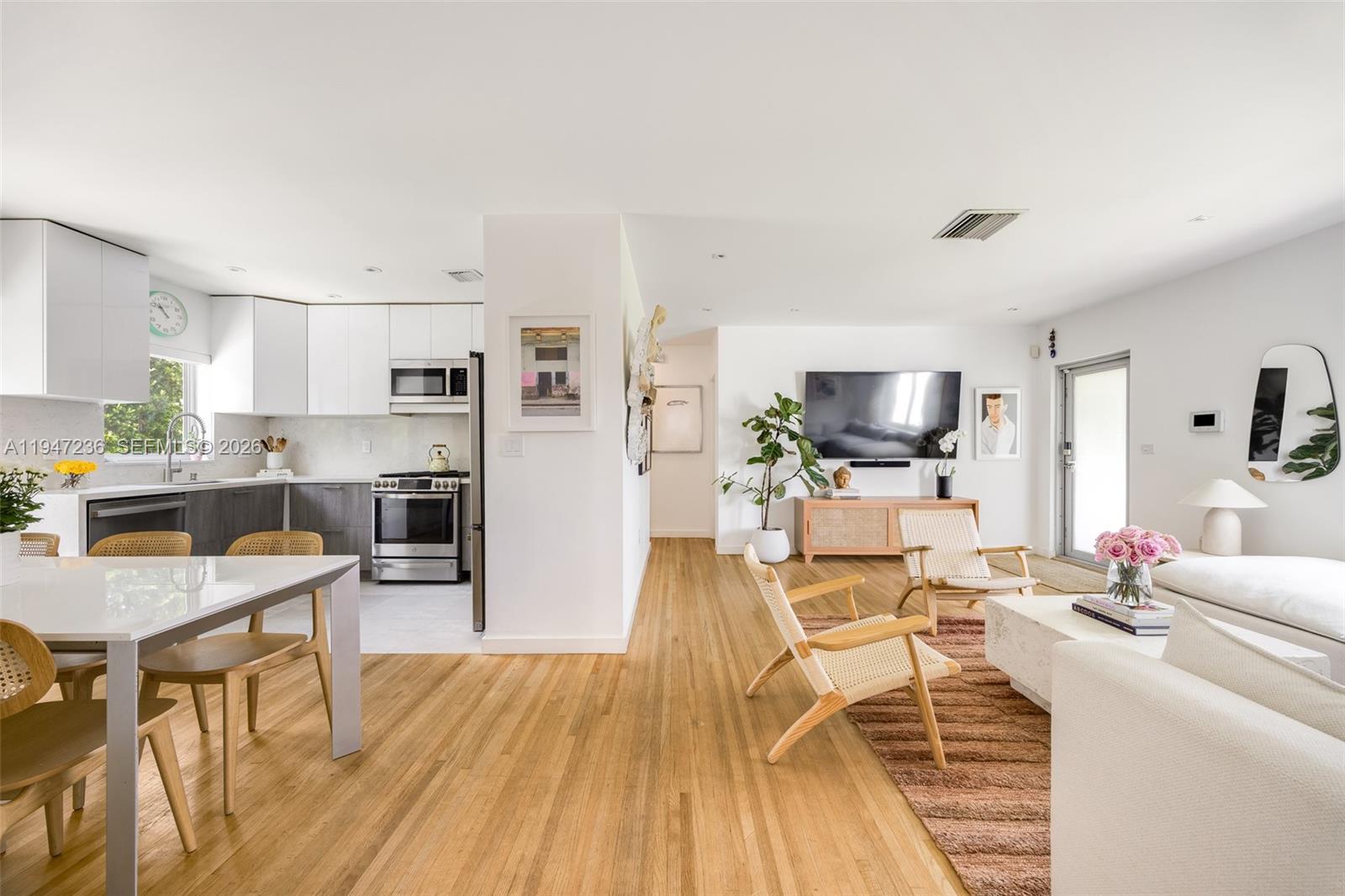 a living room with furniture a flat screen tv and kitchen view