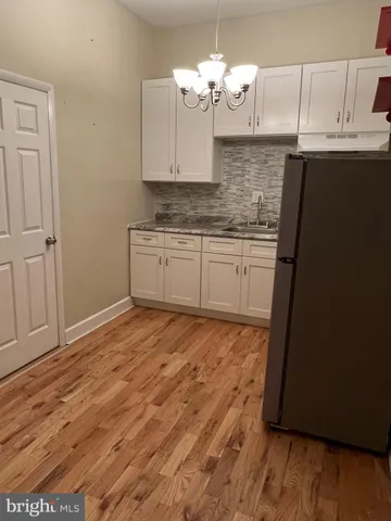 a kitchen with stainless steel appliances granite countertop a refrigerator a sink dishwasher a stove and white cabinets with wooden floor