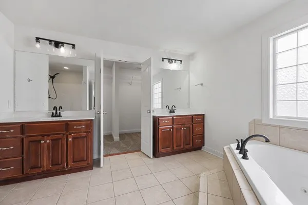 a spacious bathroom with a tub sink and mirror