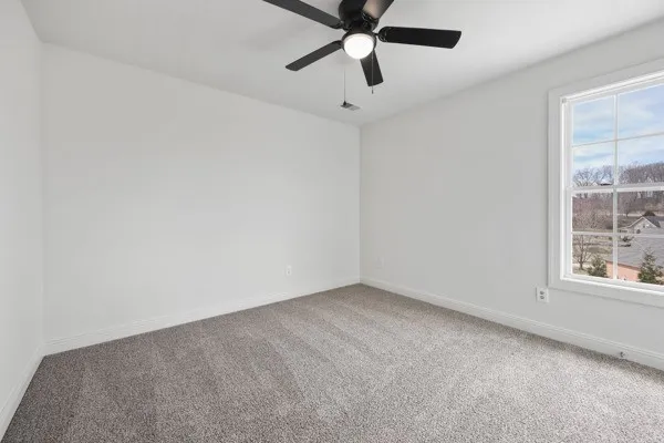 an empty room with ceiling fan and windows