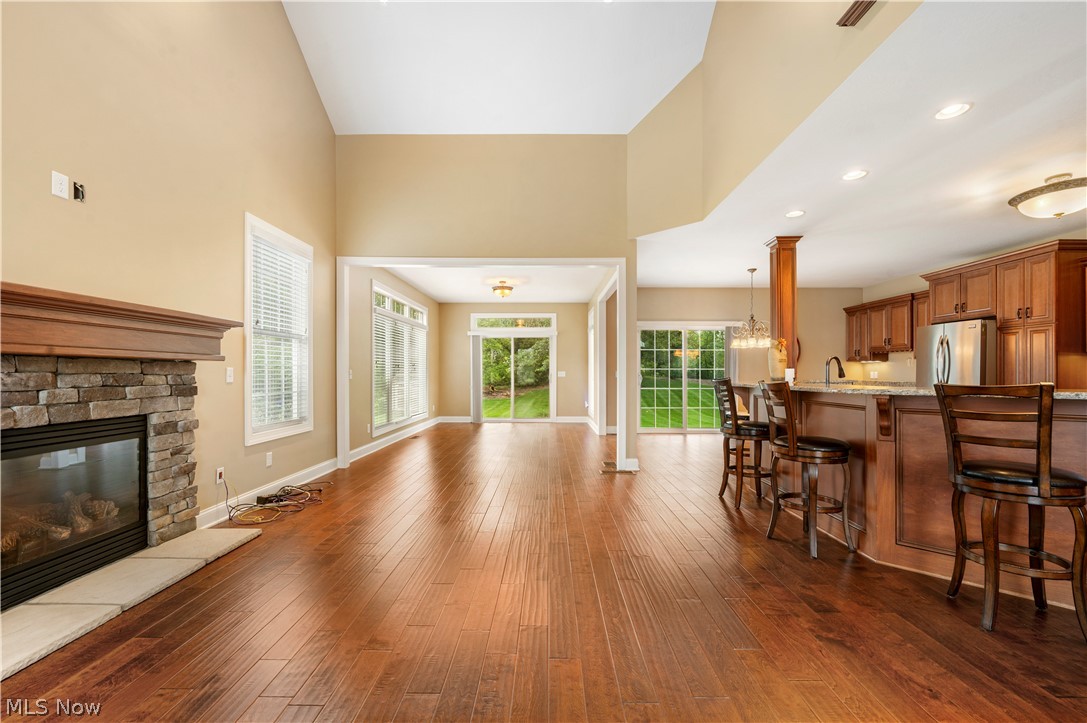3356 Huntcliffe Road Northeast Canton, OH 44721 - Photo 21 of 50 Living room featuring a stone fireplace, dark wood-type flooring, and a towering ceiling