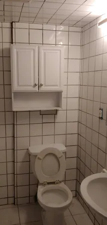 a view of a hallway with a refrigerator and cabinets