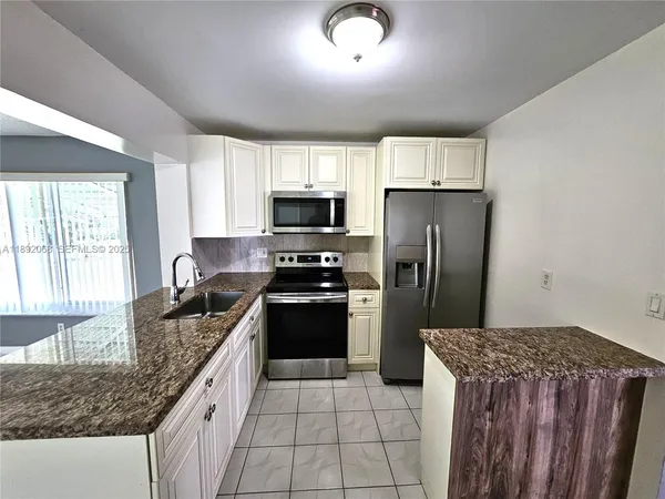 a kitchen with granite countertop a refrigerator stove and sink