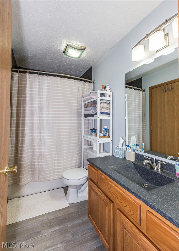 366 West Waterloo Road Akron, OH 44314 - Photo 17 of 30 Full bathroom with shower / tub combo with curtain, vanity, hardwood / wood-style flooring, toilet, and a textured ceiling
