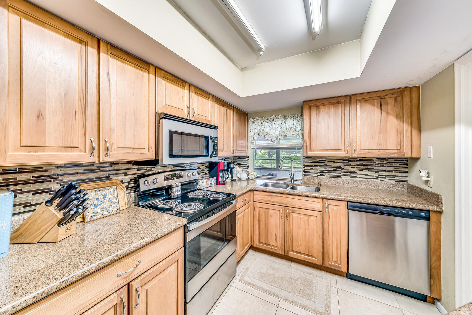 22243 Southwest 64th Way Boca Raton, FL 33428 - Photo 11 of 47 a kitchen with stainless steel appliances granite countertop a sink a stove and cabinets