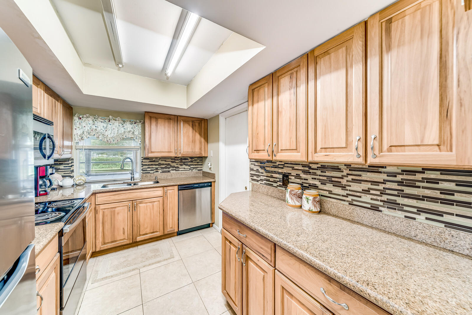 22243 Southwest 64th Way Boca Raton, FL 33428 - Photo 10 of 47 a kitchen with stainless steel appliances granite countertop a stove a sink and a microwave