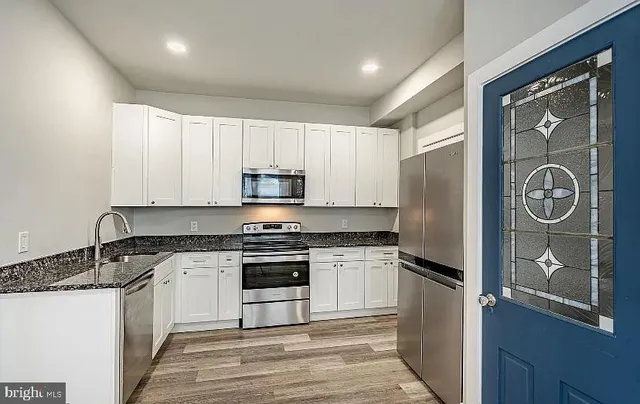 a kitchen with stainless steel appliances granite countertop a stove a refrigerator and a granite counter tops with wooden floors