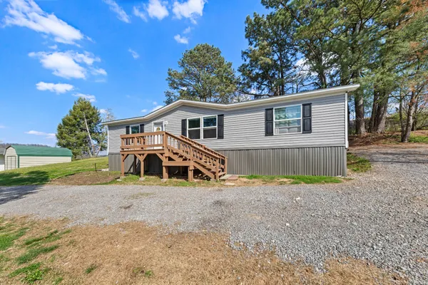 a view of a house with a yard and large trees