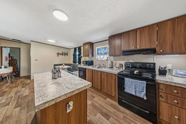 a kitchen with granite countertop a sink a stove and cabinets