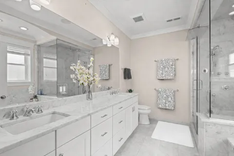 a spacious bathroom with double vanity a mirror and a shower