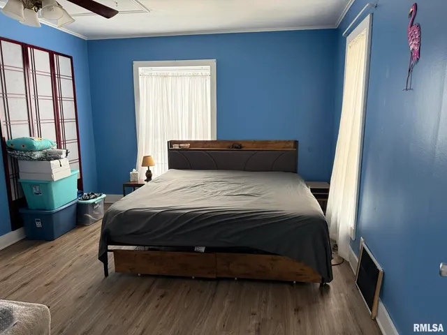 a bedroom with a bed wooden floor and window