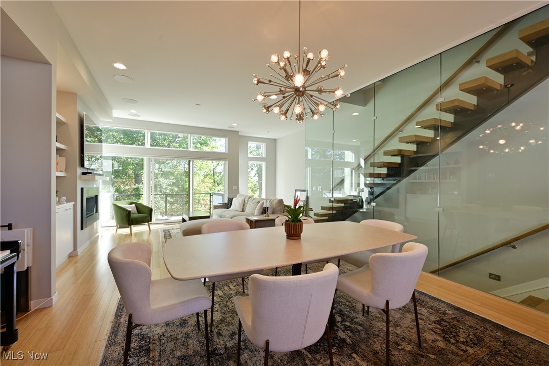 18875 Riversouth Fairview Park, Unit 30 Cleveland, OH 44126 - Photo 4 of 39 Dining room featuring stairway, a fireplace, a chandelier, light wood-style floors, and recessed lighting