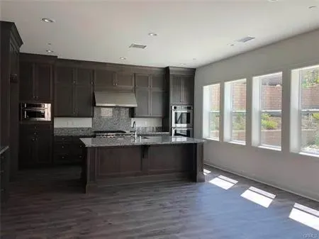 a large kitchen with granite countertop a stove a sink and a refrigerator