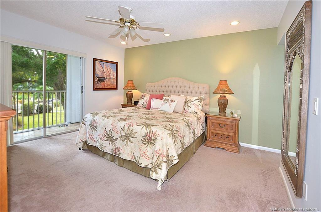1854 Southwest Palm City Road, Unit 203 Stuart, FL 34994 - Photo 22 of 38 Wake up to serene green views from your spacious primary suite, complete with direct access to the lanai—perfect for enjoying your morning coffee in the fresh Florida air.