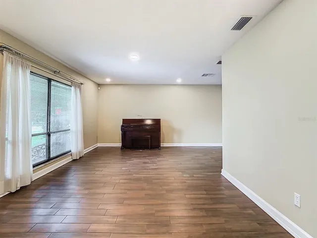 a view of an empty room with wooden floor and windows