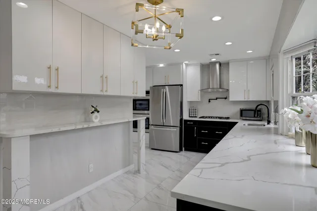 a large white kitchen with lots of counter space a sink and stainless steel appliances