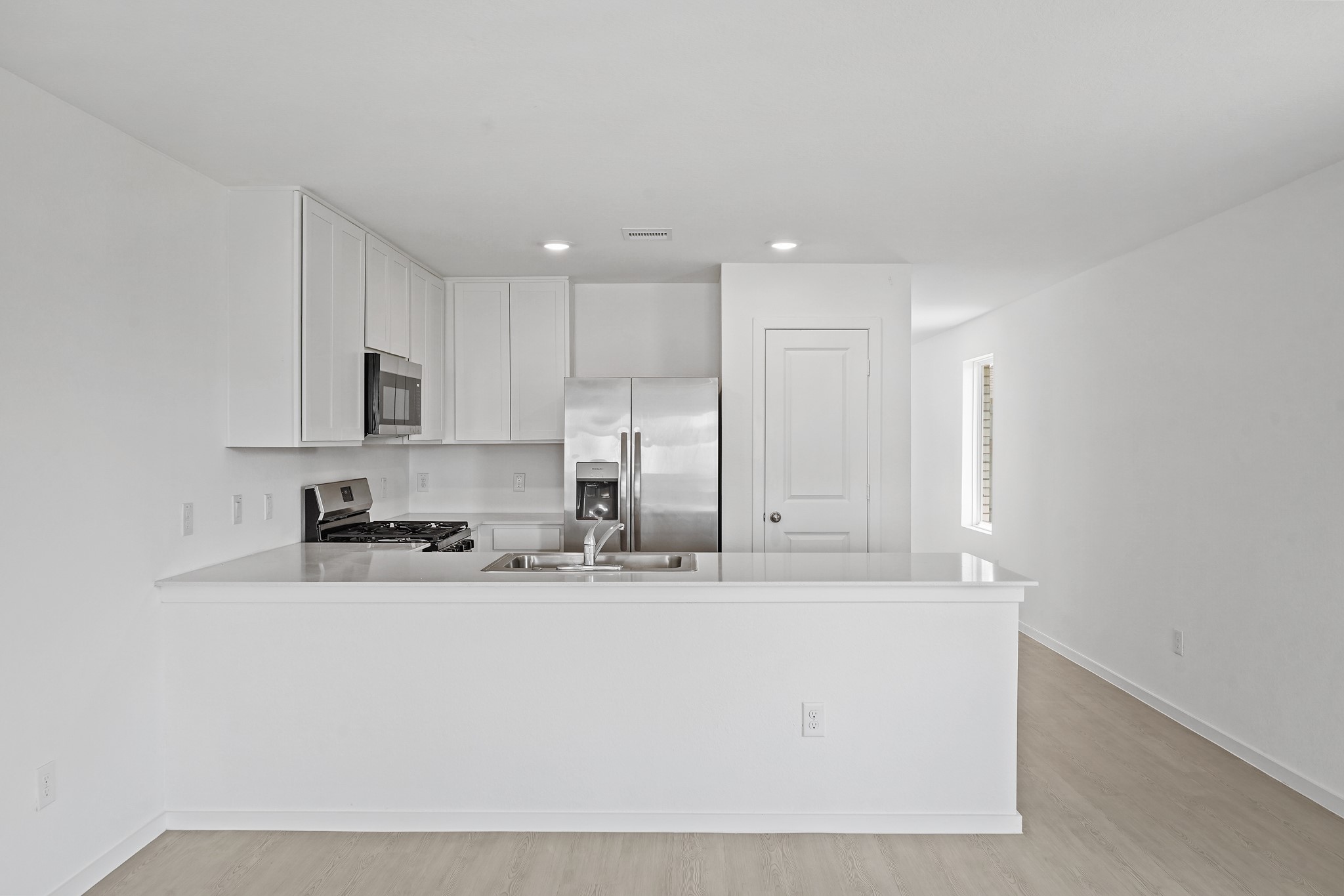 26931 Feather Reed Drive Katy, TX 77493 - Photo 3 of 16 The kitchen space features a spacious breakfast bar, bright quartz countertops, modern stainless steel appliances, white cabinetry, and an open view into the living areas.