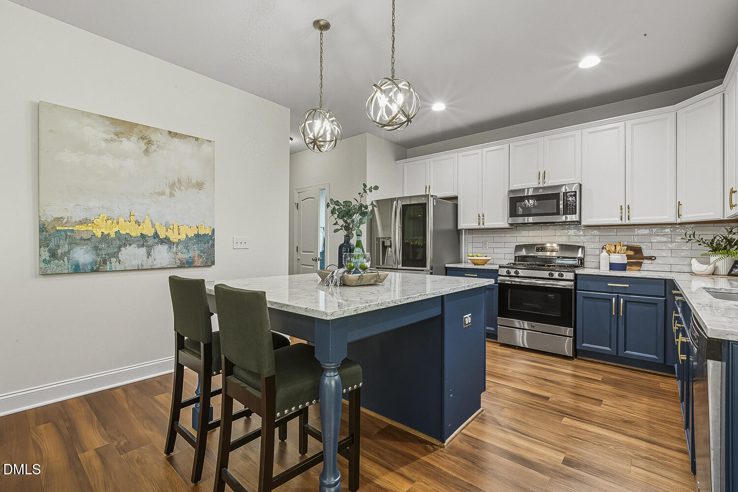 5180 Copain Cove Fuquay-Varina, NC 27526 - Photo 13 of 45 a kitchen with stainless steel appliances granite countertop a stove top oven a refrigerator a sink and a dining table with wooden floor