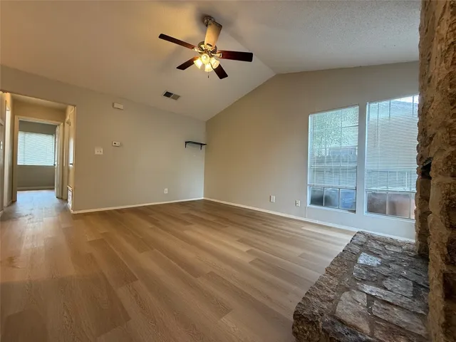a view of an empty room and chandelier fan