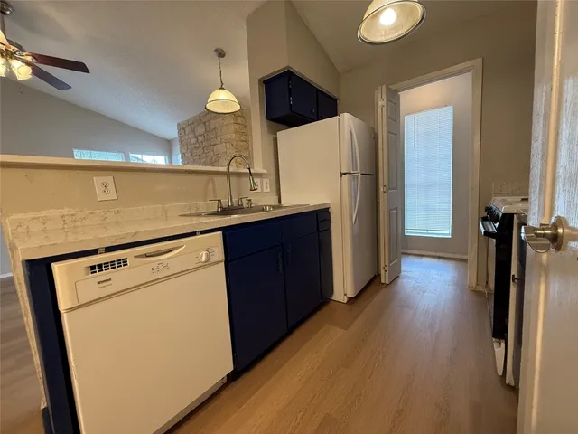 a kitchen with sink a refrigerator and wooden floor