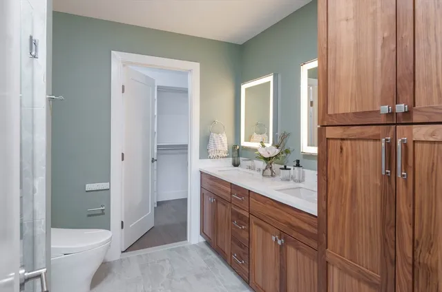 a bathroom with a double vanity sink toilet mirror and bathtub