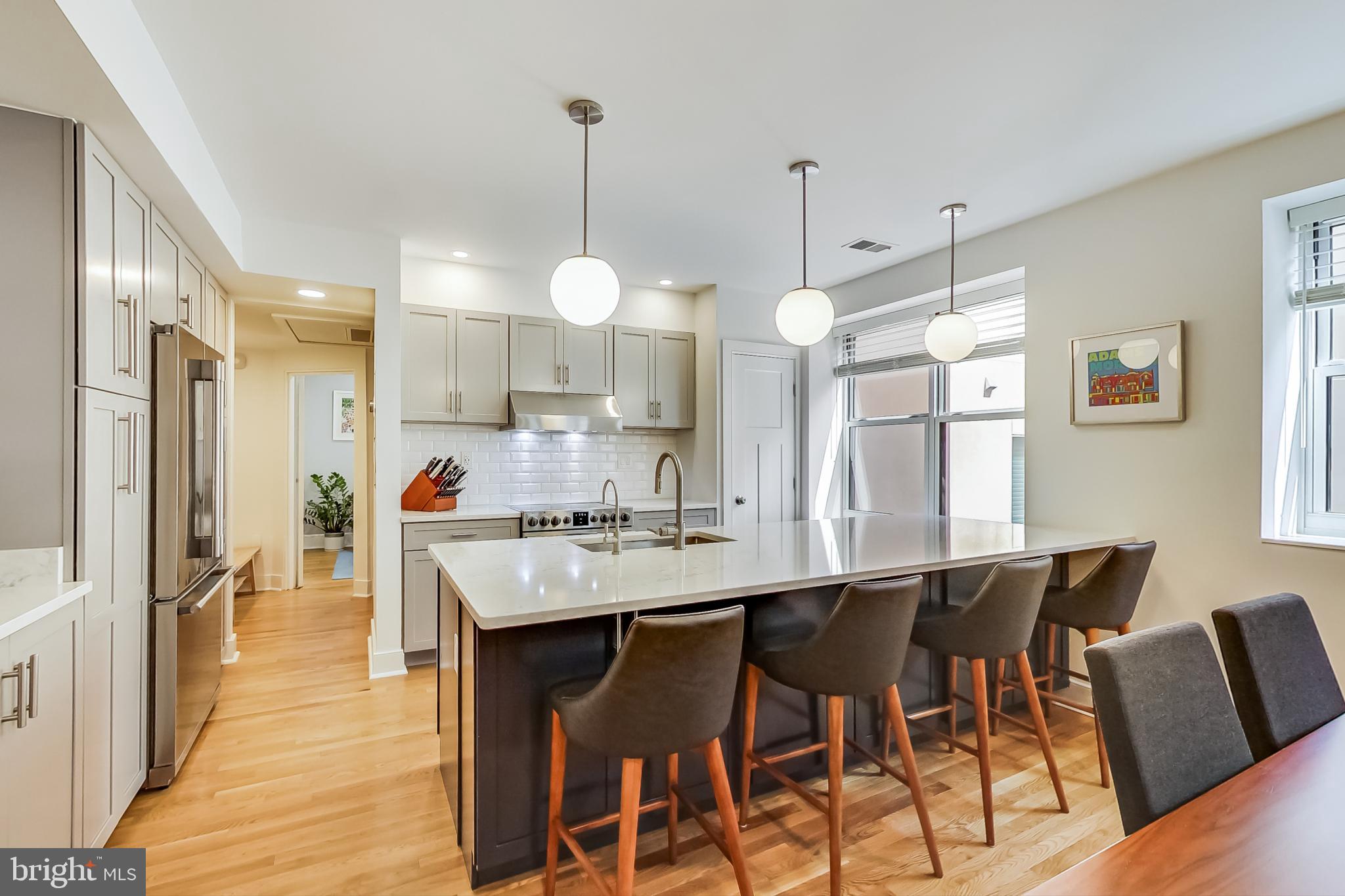 a kitchen with stainless steel appliances kitchen island granite countertop a table chairs and a wooden floor