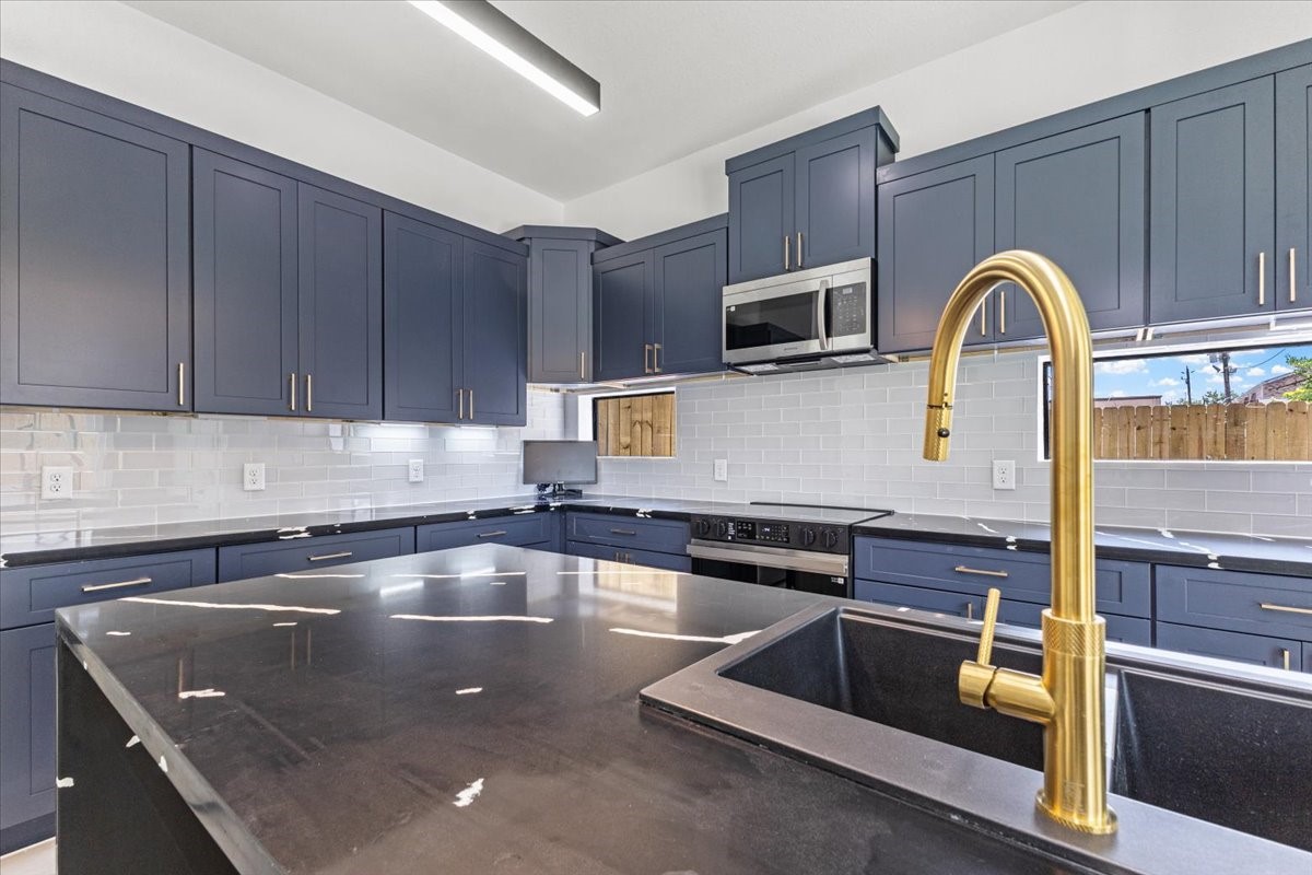 5110 Longmeadow Street, Unit B Houston, TX 77033 - Photo 12 of 25 a kitchen with stainless steel appliances granite countertop a sink a microwave and wooden cabinets