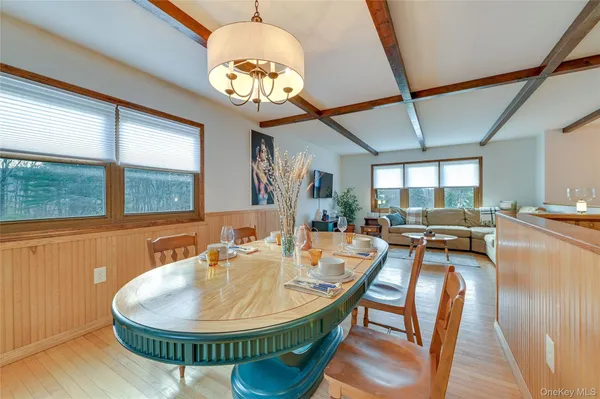 a dining room with wooden floor a chandelier a wooden table and chairs