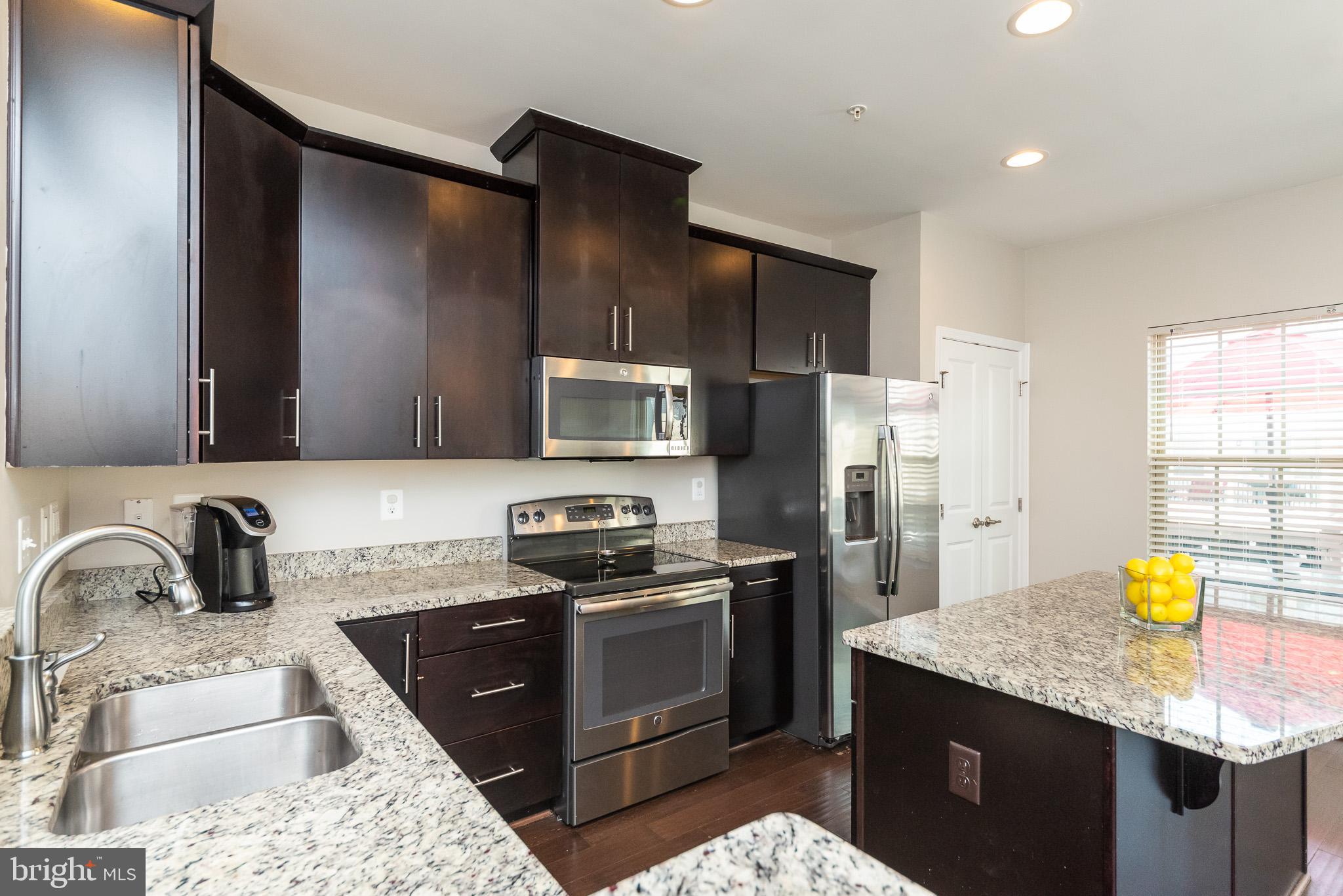 1038 Ramble Run Road Baltimore, MD 21220 - Photo 20 of 47 a kitchen with stainless steel appliances kitchen island granite countertop a sink a stove a refrigerator a stove a counter space and cabinets