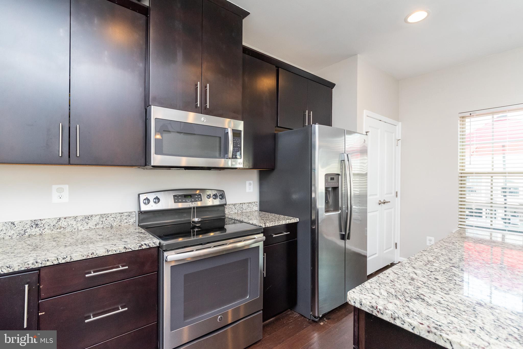 1038 Ramble Run Road Baltimore, MD 21220 - Photo 28 of 47 a kitchen with stainless steel appliances granite countertop a stove microwave refrigerator and sink