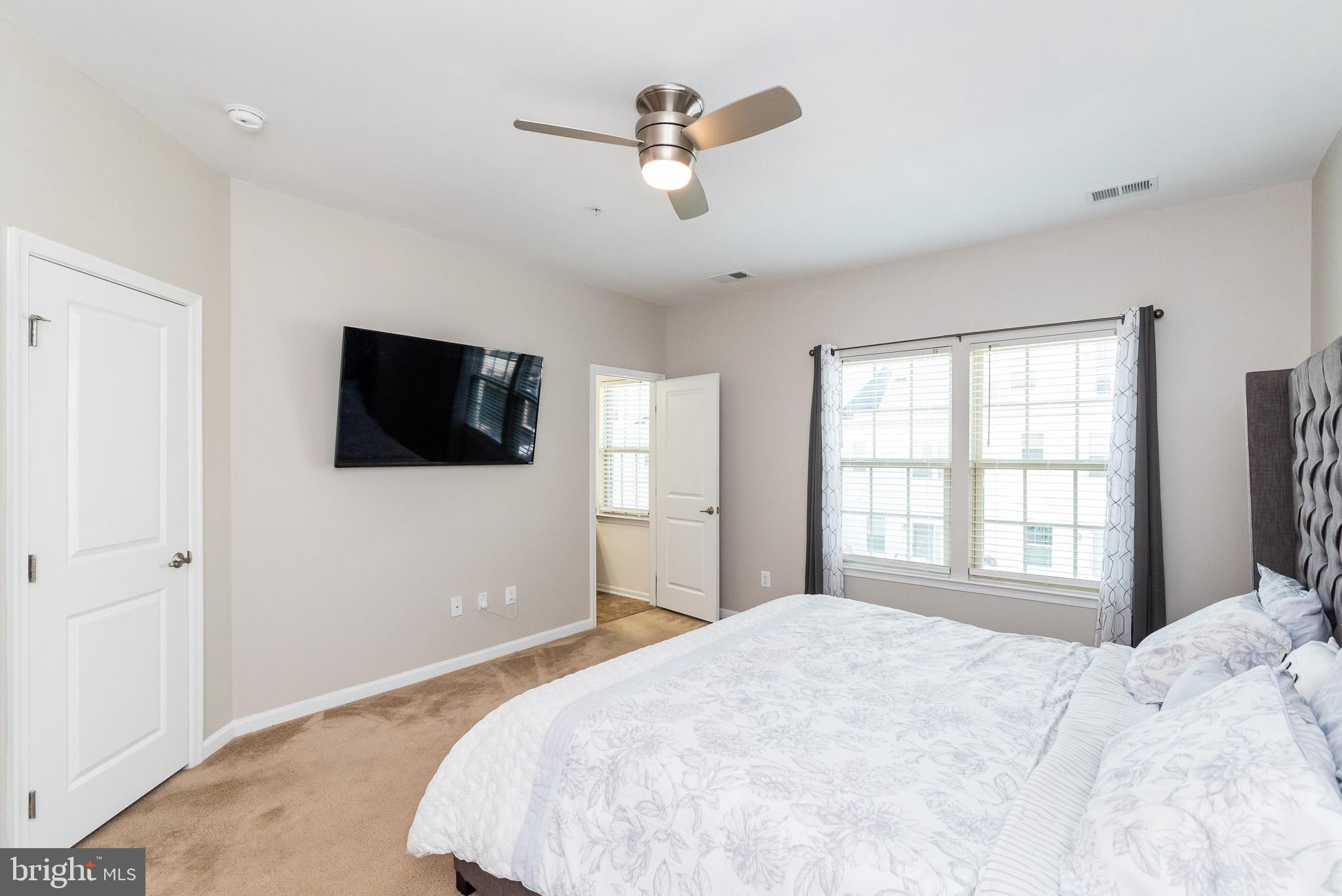 1038 Ramble Run Road Baltimore, MD 21220 - Photo 31 of 47 a bedroom with a large bed a flat tv screen and a ceiling fan