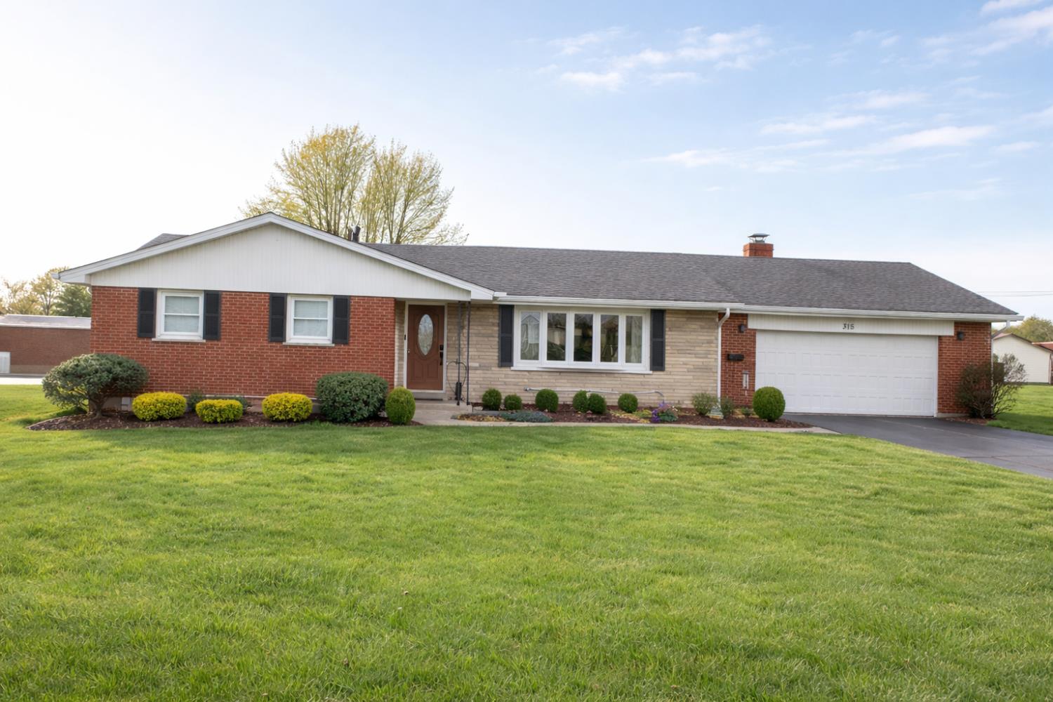 315 Nieman Street Sunman, IN 47041 - Photo 1 of 30 Well-maintained brick ranch offering classic curb appeal with a spacious front yard and mature landscaping. The inviting exterior features a covered entry, attached garage, and a clean, timeless design in a desirable setting. Note: Exterior image enhanced for brightness and color balance to reflect true-to-life appearance.