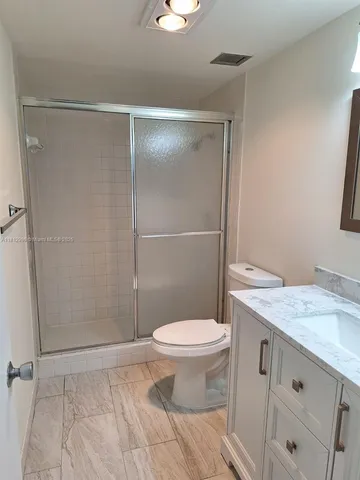 a bathroom with a granite countertop toilet sink and mirror