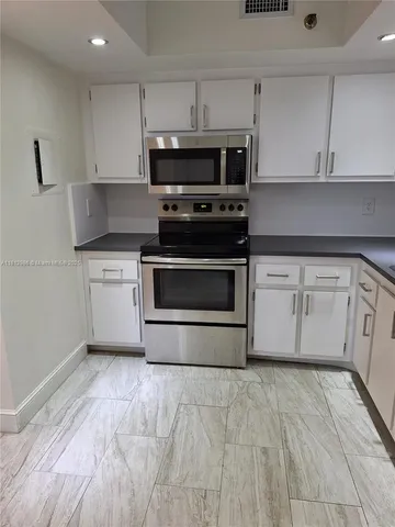 a kitchen with granite countertop a stove a microwave a sink and cabinets