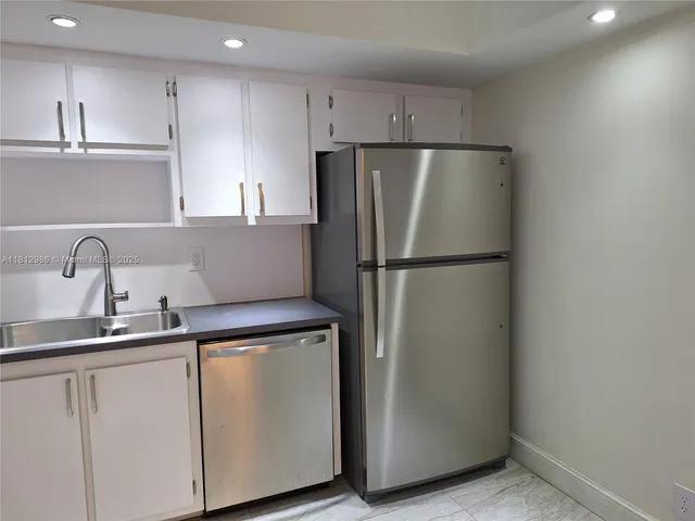 a kitchen with a refrigerator sink and cabinets