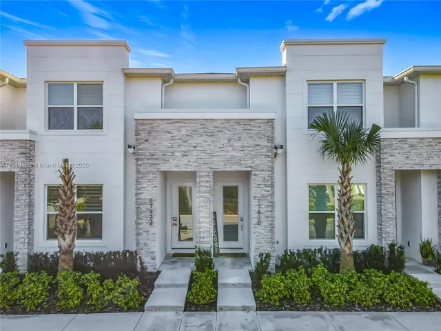 a front view of a house with a yard and potted plants