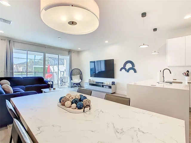 a kitchen with a refrigerator a stove a sink and a dining table with wooden floor