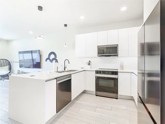 a kitchen with stainless steel appliances granite countertop a refrigerator sink and white cabinets