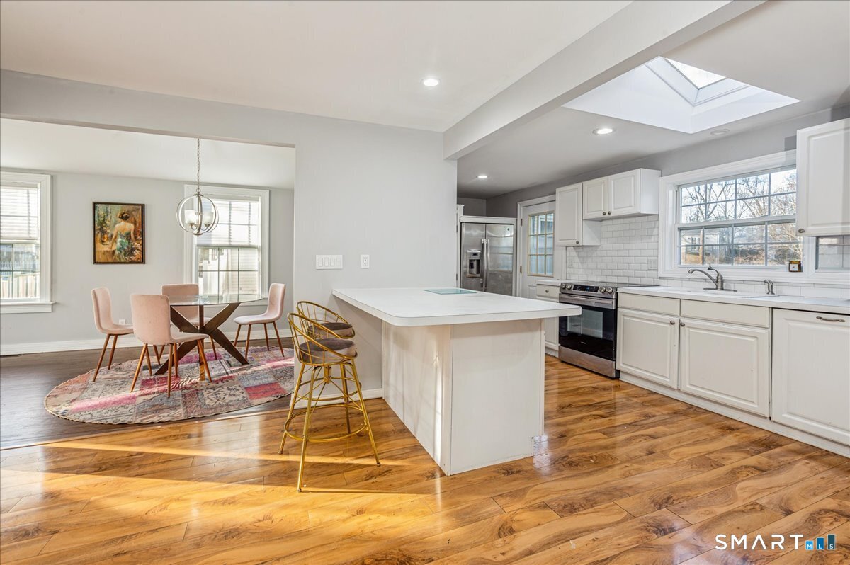 11 Margaret Street Norwalk, CT 06851 - Photo 12 of 26 a kitchen with stainless steel appliances granite countertop a stove top oven a sink a dining table and chairs with wooden floor