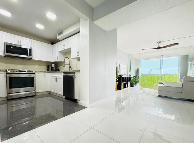a living room with stainless steel appliances kitchen island granite countertop a stove and a sink