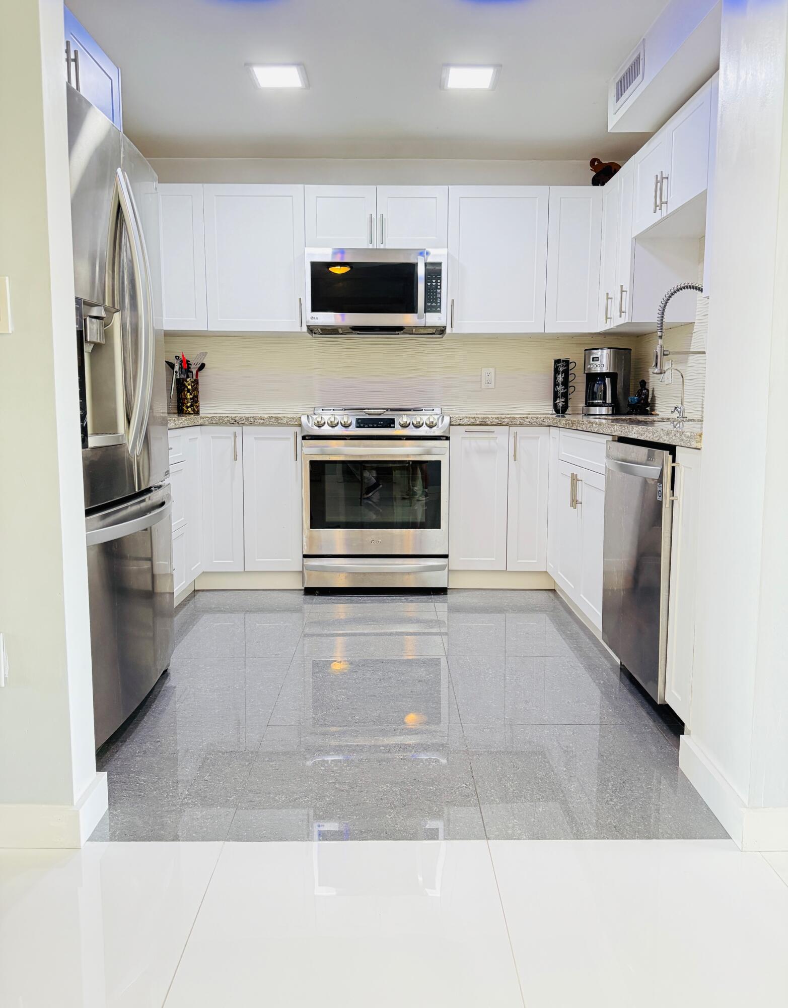 4164 Inverrary Drive, Unit 404 Lauderhill, FL 33319 - Photo 4 of 23 a kitchen with stainless steel appliances a stove microwave and a refrigerator