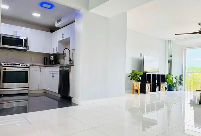 a kitchen with stainless steel appliances kitchen island granite countertop a refrigerator a stove top oven a sink a counter space and cabinets