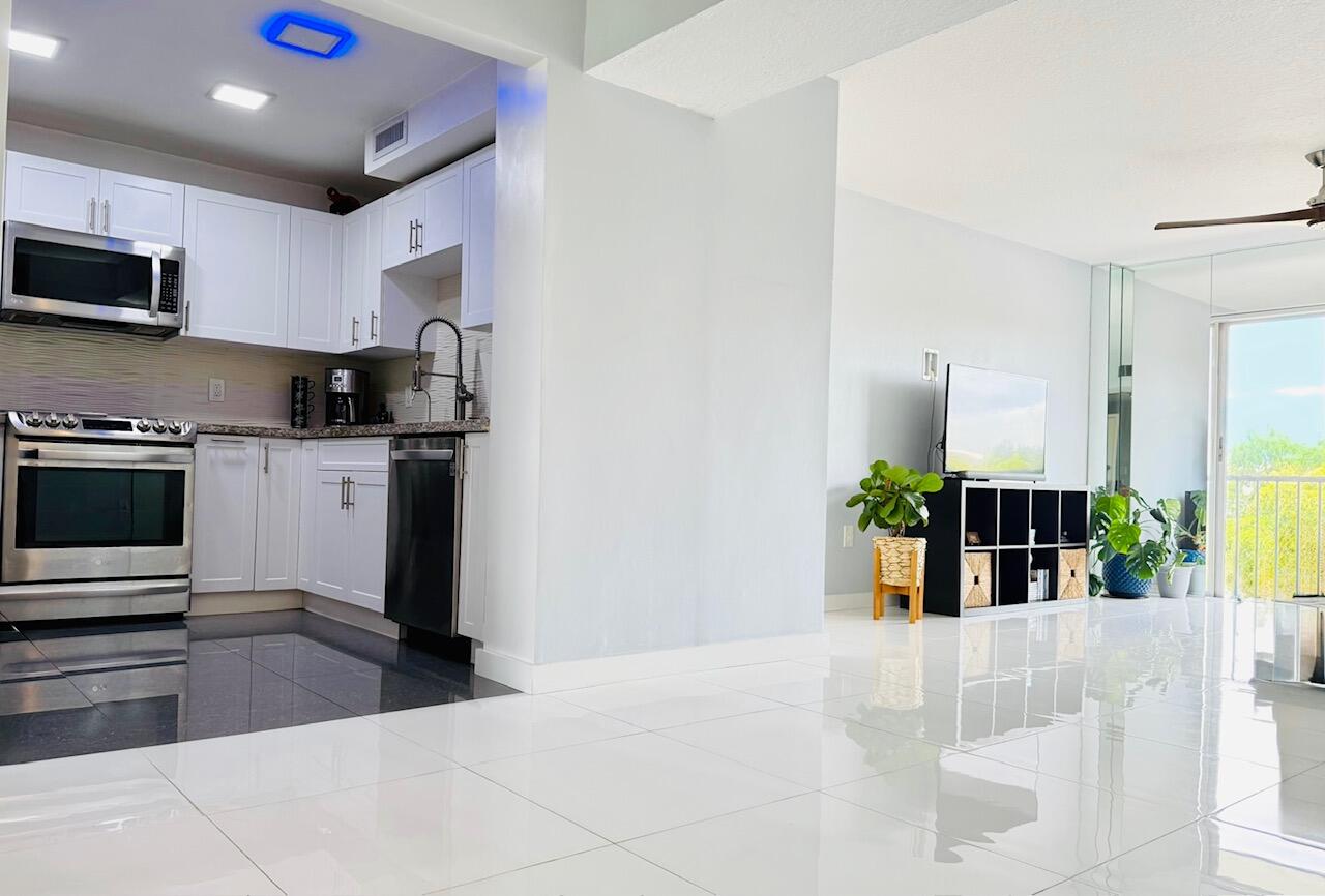 4164 Inverrary Drive, Unit 404 Lauderhill, FL 33319 - Photo 6 of 23 a kitchen with stainless steel appliances kitchen island granite countertop a refrigerator a stove top oven a sink a counter space and cabinets