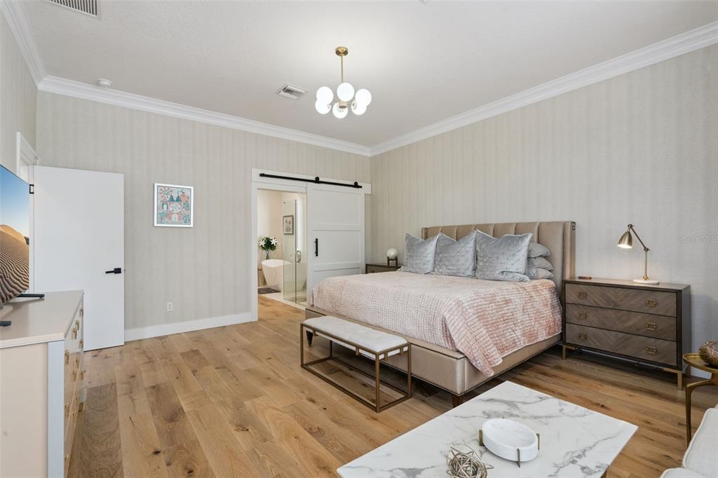 908 Croton Road Celebration, FL 34747 - Photo 29 of 86 a spacious bedroom with a bed and a chandelier
