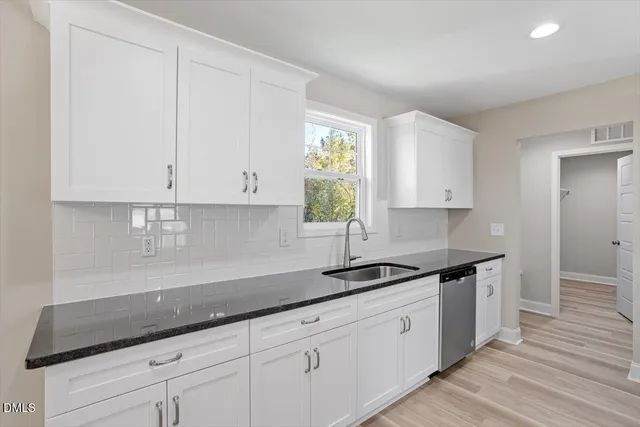 a kitchen with granite countertop white cabinets and a sink