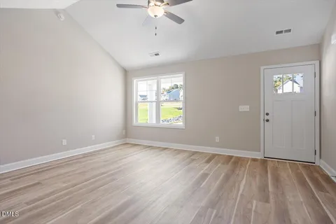 an empty room with wooden floor and windows
